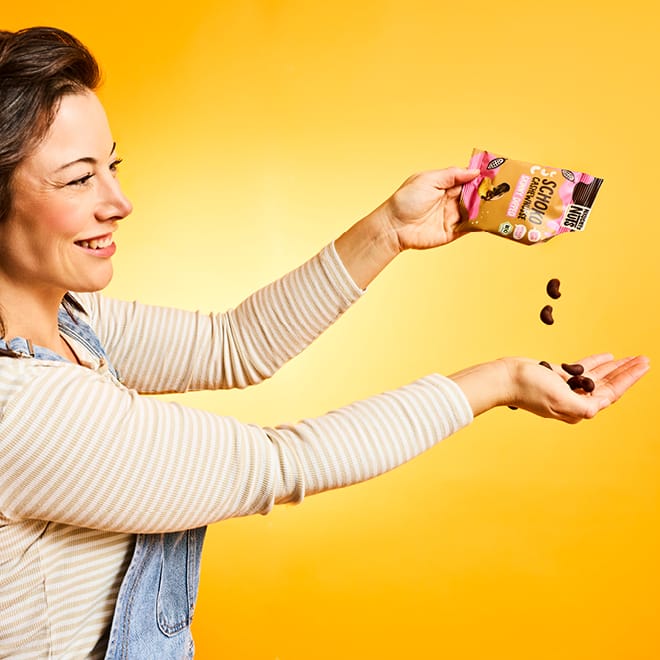 Frau schüttet Schoko-Cashew-Kerne aus einer Packung in ihre Hand