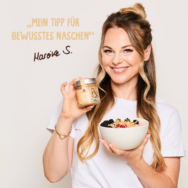 Frau hält Happy White Hazel Creme und eine Schüssel mit Beeren und Creme