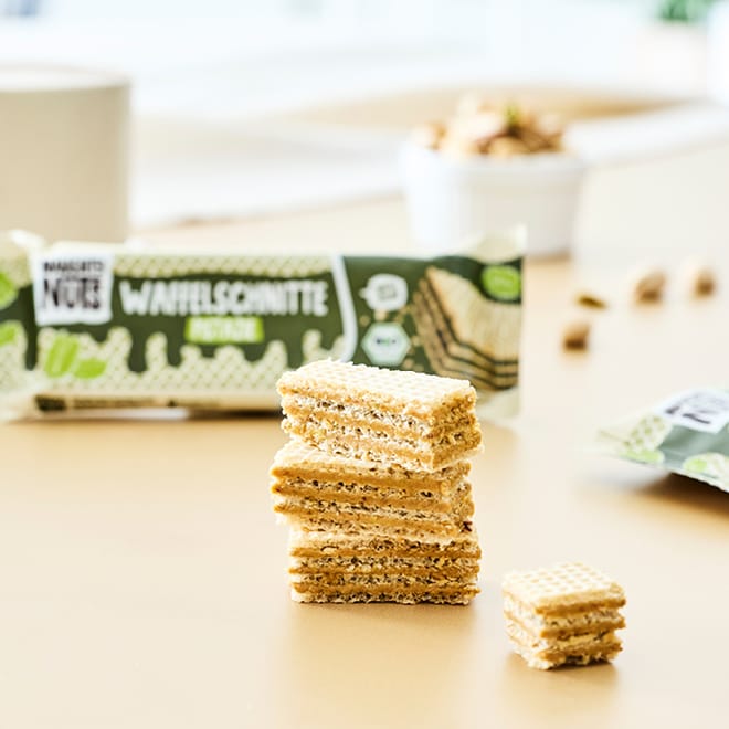 Bio Waffelschnitte Mixed Box Nuss-Nougat & Pistazie gestapelt mit Verpackung im Hintergrund